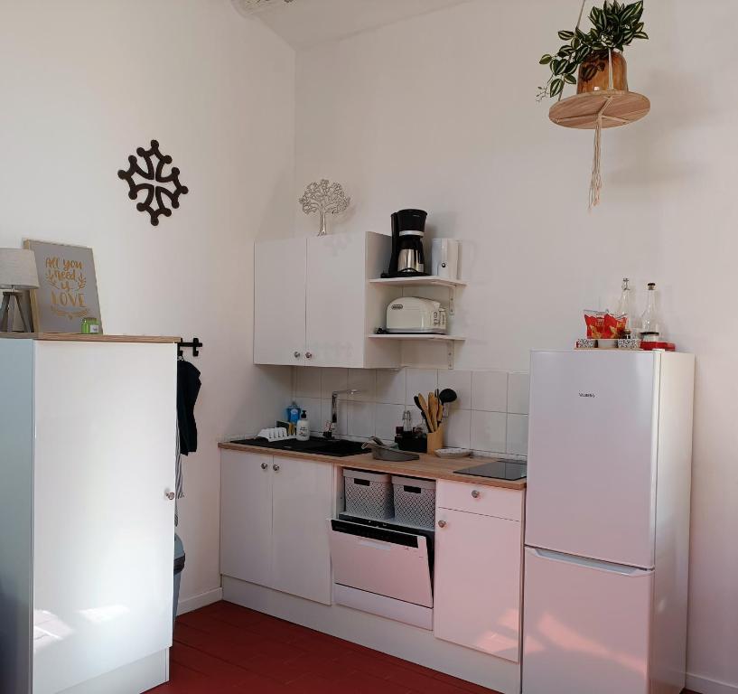 eine Küche mit weißen Schränken und einem weißen Kühlschrank in der Unterkunft la guitoune du pélican halte à vélo in Puisserguier