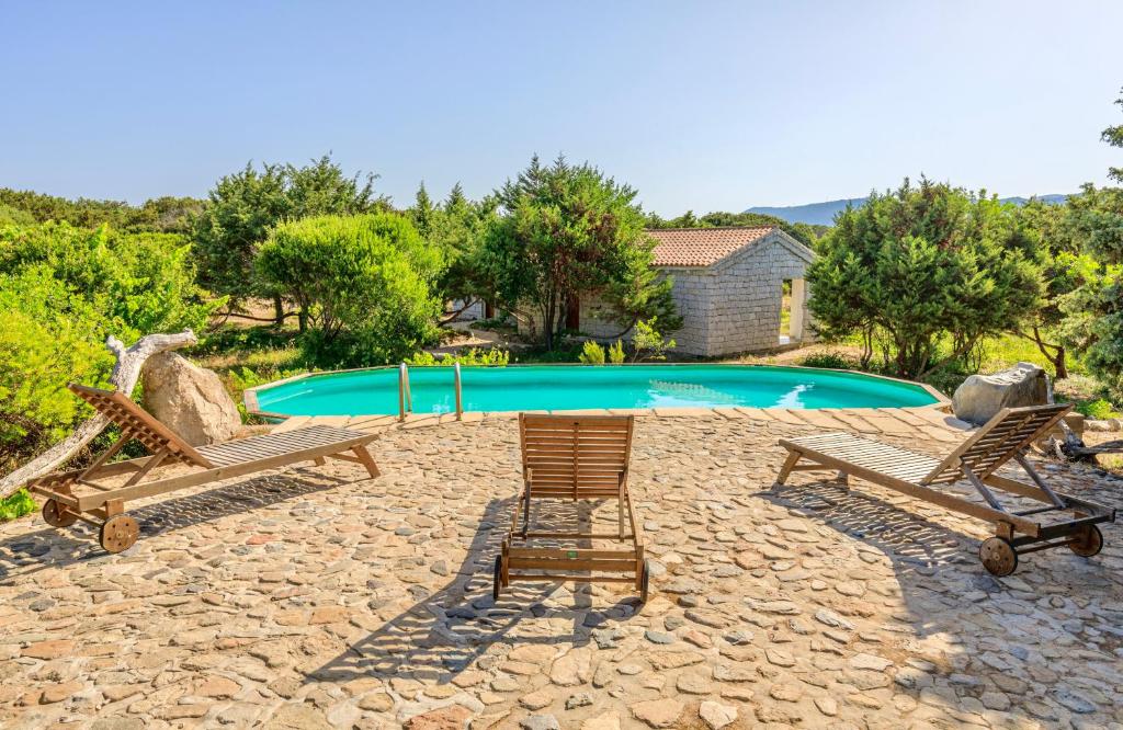 a swimming pool with two chairs and a table at ISA - Residence with swimming pool in Badesi just 300 mt from the sea in Badesi