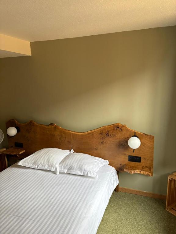 a bedroom with a bed with a wooden headboard at Hotel le Chasseur in Illkirch-Graffenstaden