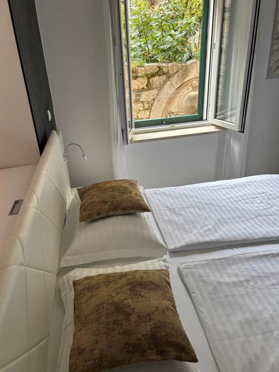 a bedroom with a bed with two pillows and a window at Studio Apartman Fictilis in Split