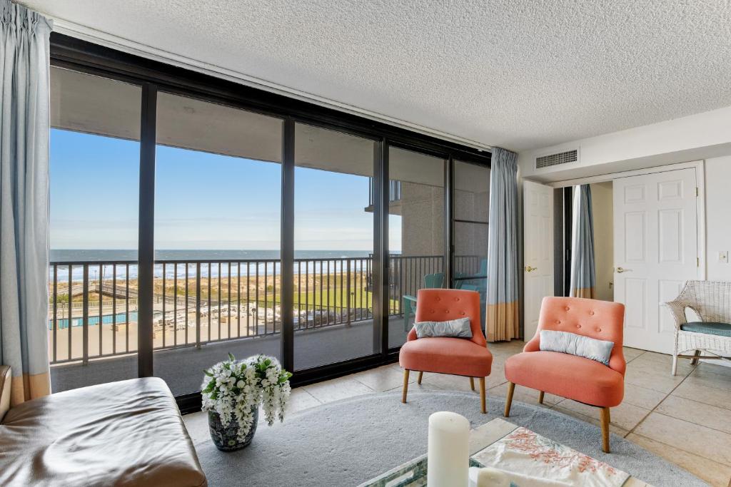 a bedroom with a bed and two chairs and a balcony at Sea Colony - 301S Edgewater House Rd in Bethany Beach