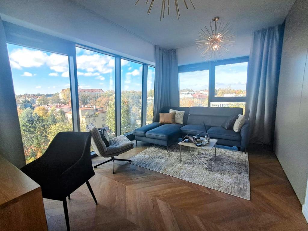 ein Wohnzimmer mit einem blauen Sofa und großen Fenstern in der Unterkunft Olszynki Park City View in Rzeszów