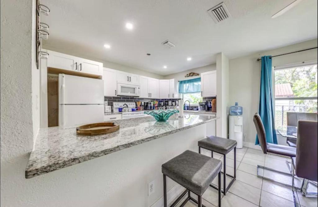 a kitchen with white cabinets and a counter with stools at Downtown Lake Worth Retreat in Lake Worth Corridor