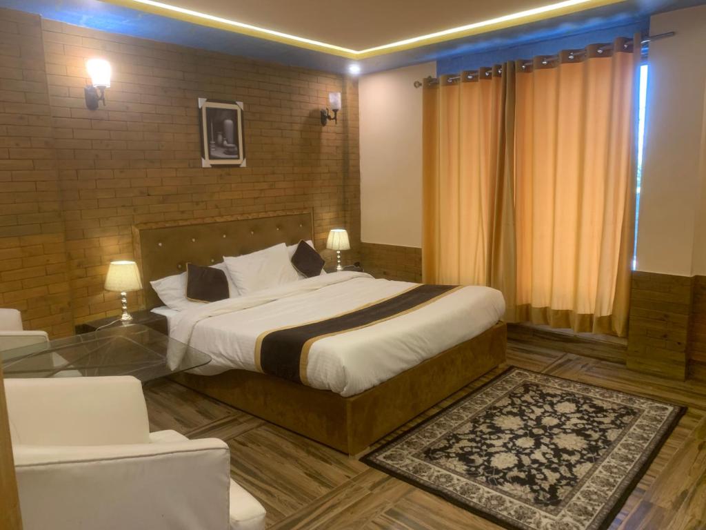 Habitación de hotel con cama y silla en Green Executive Hotel, en Nathia Gali