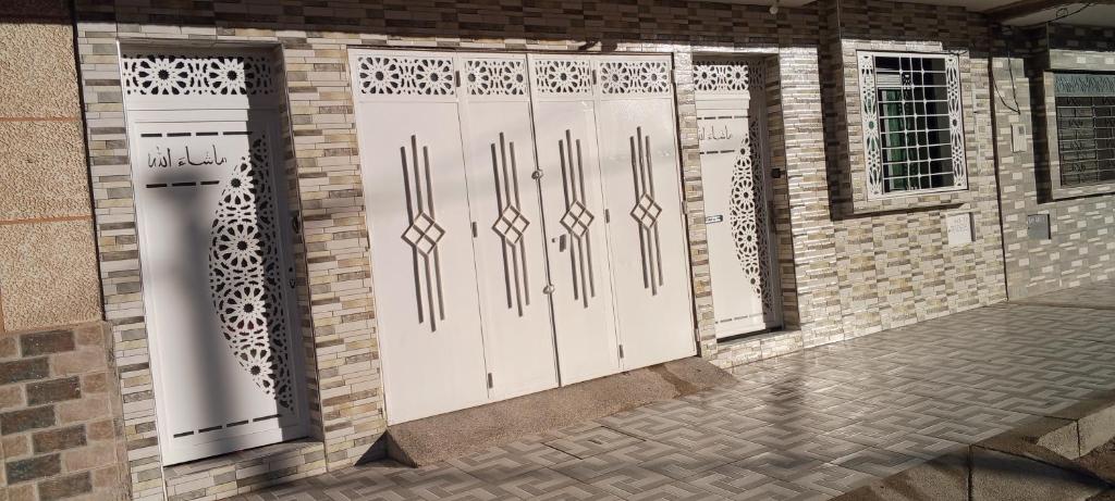 un ensemble de portes blanches sur un bâtiment en briques dans l'établissement Maison confortable au plein milieu d'Oujda, bien équipée et sécurisée avec 2 chambres et salon moderne et un garage pour le véhicule, cuisine et un douche moderne et une toilette marocaine, à Oujda