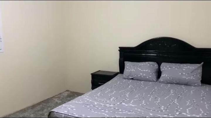 a bed with a black headboard and two pillows at منتزه السلامة Parc ASSALAMA in Kenitra