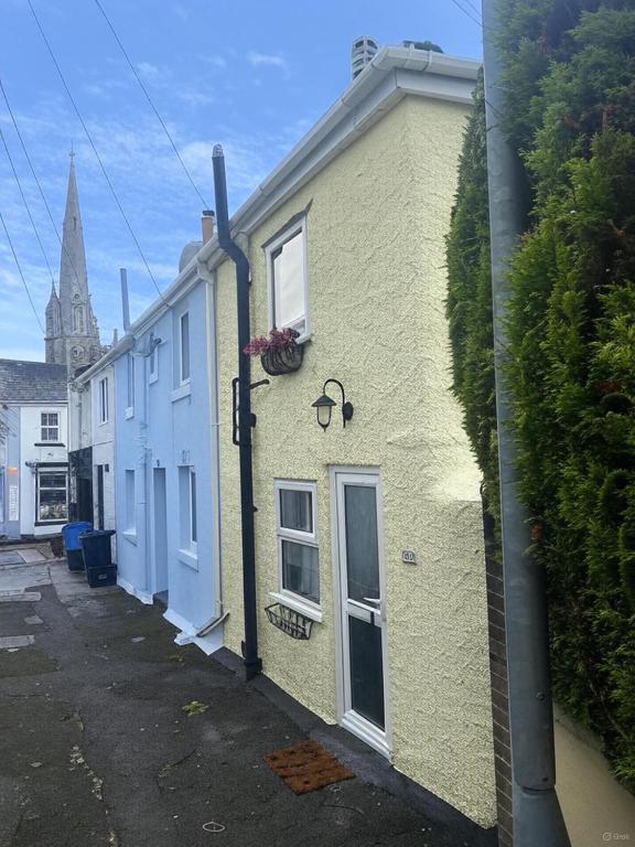 a yellow building with a window on a street at Cosy cottage in Torquay