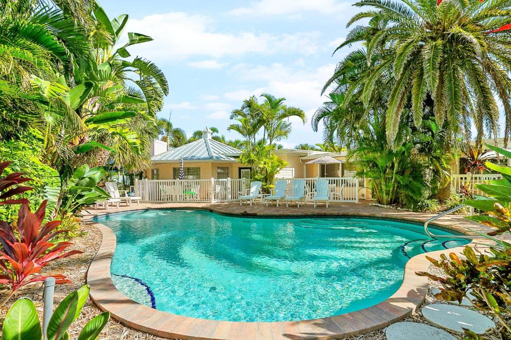 a swimming pool with palm trees and a house at Anna Cabana Bungalow #1 in Holmes Beach