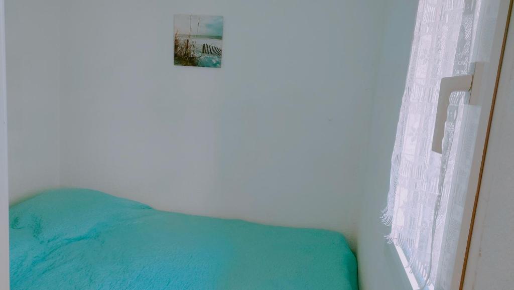 une chambre avec un lit bleu et une fenêtre dans l'établissement Zenitude Corniche charmant studio cabine vue mer, à Sète