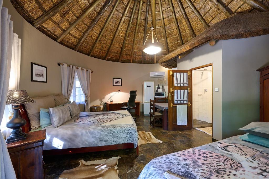 a bedroom with two beds and a wooden ceiling at Mokolodi Backpackers in Gaborone