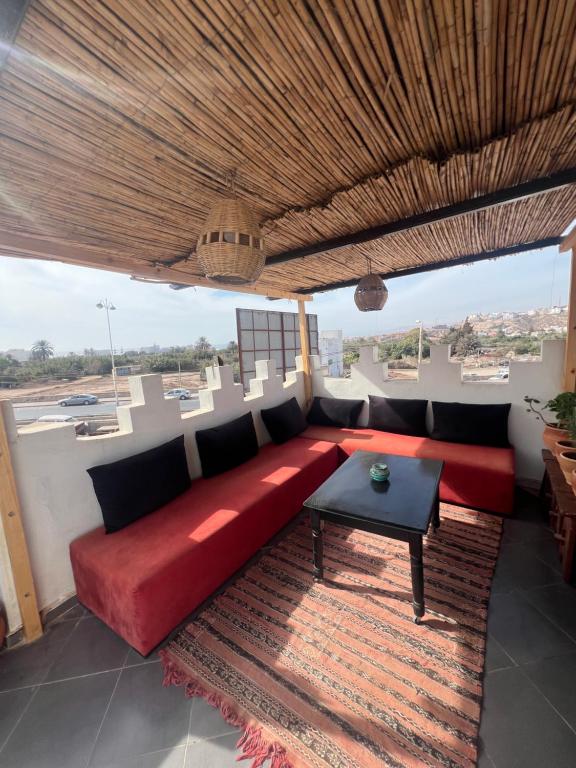 a living room with a red couch and a table at Dar Amzil in Aourir