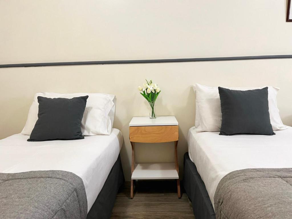 ブエノスアイレスにあるAlpino Hotelのテーブルに花瓶を飾った客室のベッド2台
