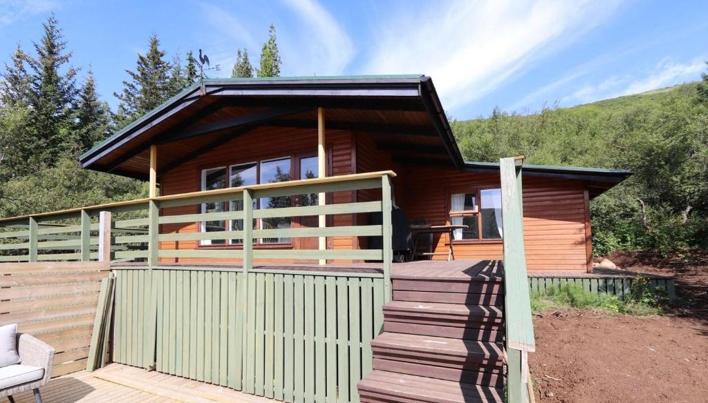 een houten huis met een hek en een veranda bij Cosy Cabin Escape with Hot Tub & Lake View in Lundur