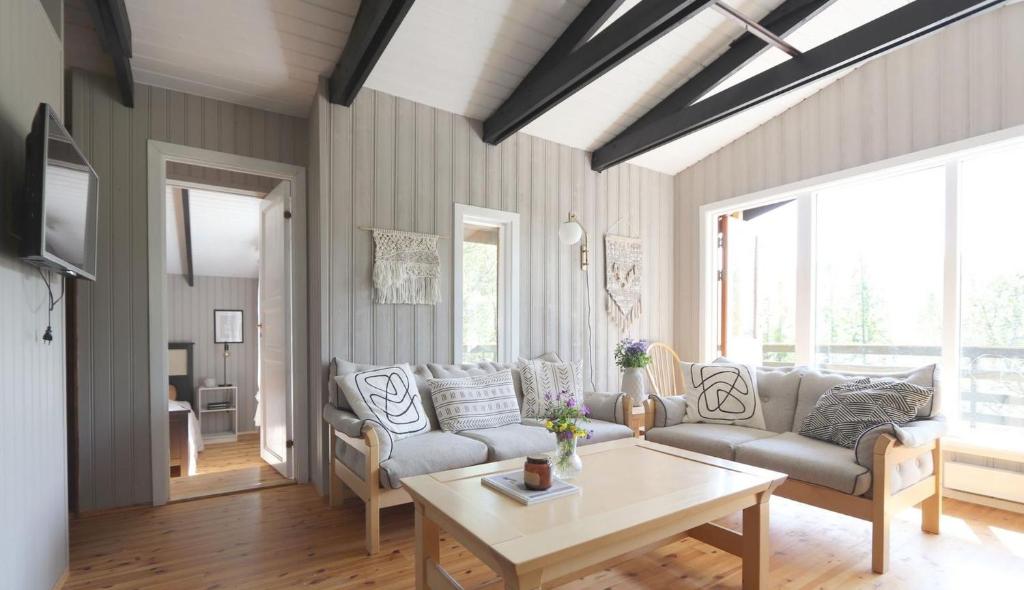 ein Wohnzimmer mit Sofa und Tisch in der Unterkunft Cosy Cabin Escape with Hot Tub & Lake View in Lundur