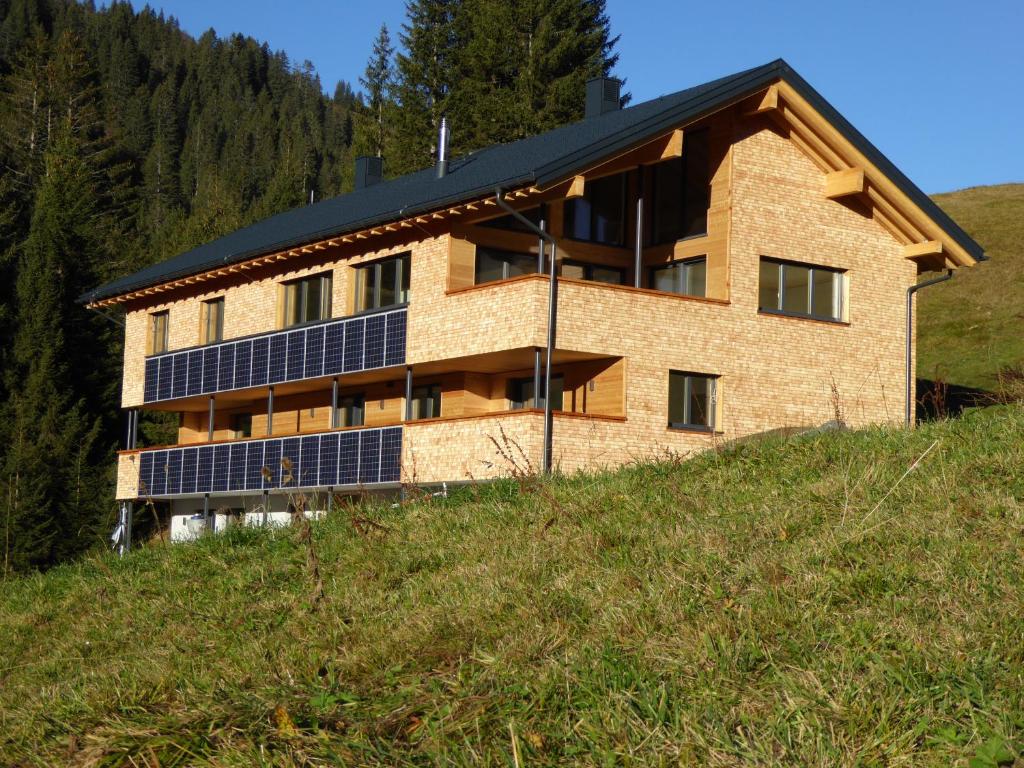 une maison avec des panneaux solaires sur le côté d'une colline dans l'établissement Flora Alpinea, à Damüls
