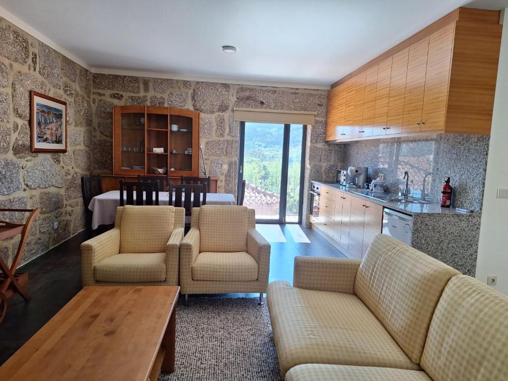 eine Küche und ein Wohnzimmer mit Sofas und einem Tisch in der Unterkunft Casa Feixa Gerês in Lordelo