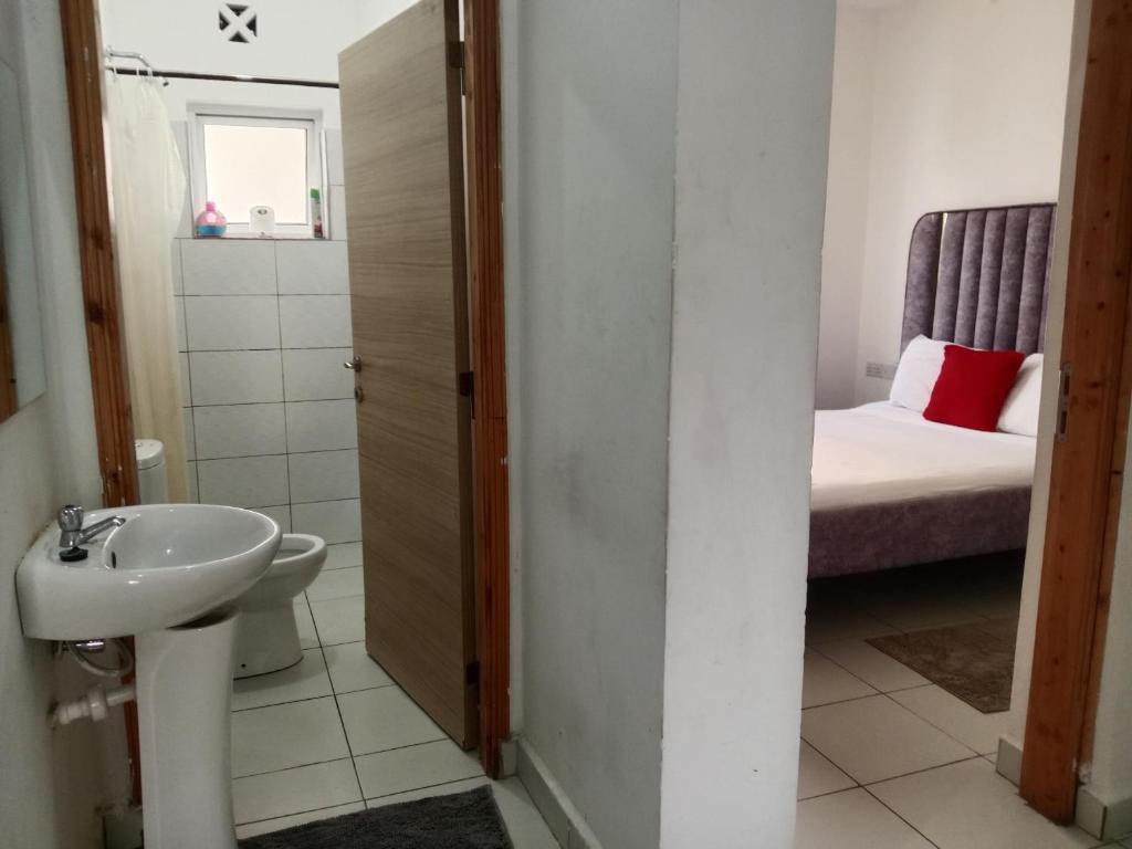 a small bathroom with a sink and a bed at Buxton Point Kandy Cozy Two Bedroom Apartment in Mombasa