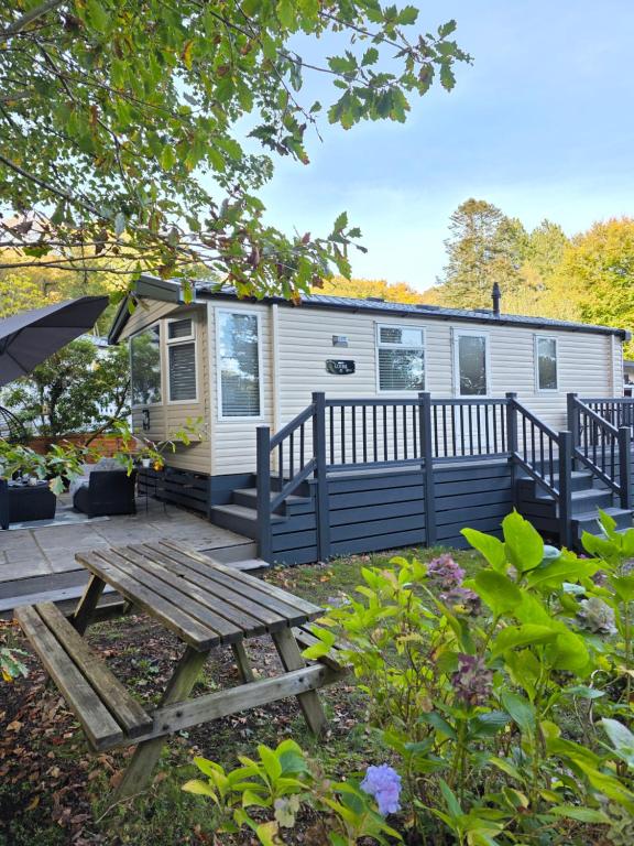 a mobile home with a picnic table and an umbrella at 'By The Stream' 60 The Beeches in Prenteg