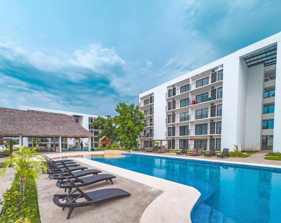 a swimming pool with lounge chairs in front of a building at Departamento Comodo con Alberca a 10min de la Playa in Mezcales