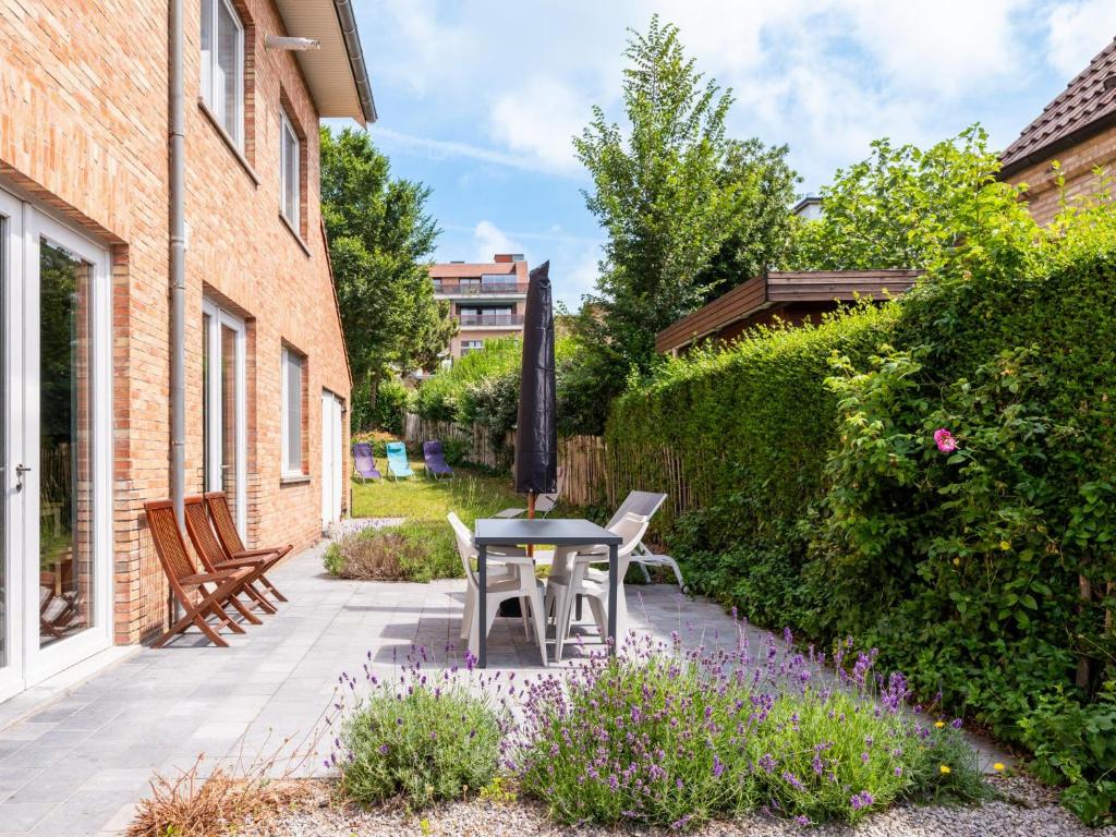 a patio with a table and chairs in a garden at La Terrasse in Sint-Idesbald