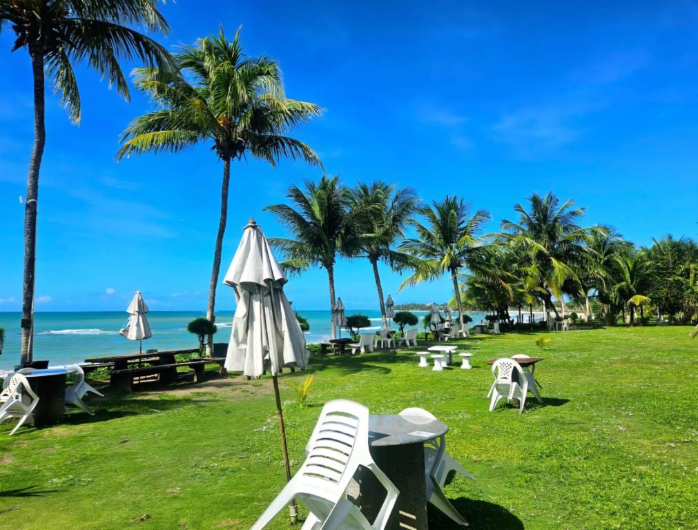 a beach with chairs and an umbrella and palm trees at Marinas Vista Mar in Tamandaré