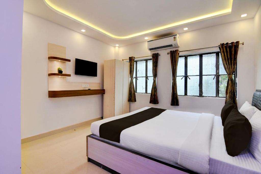 a bedroom with a bed and a tv and windows at Hotel O Acroview in Ballygunge