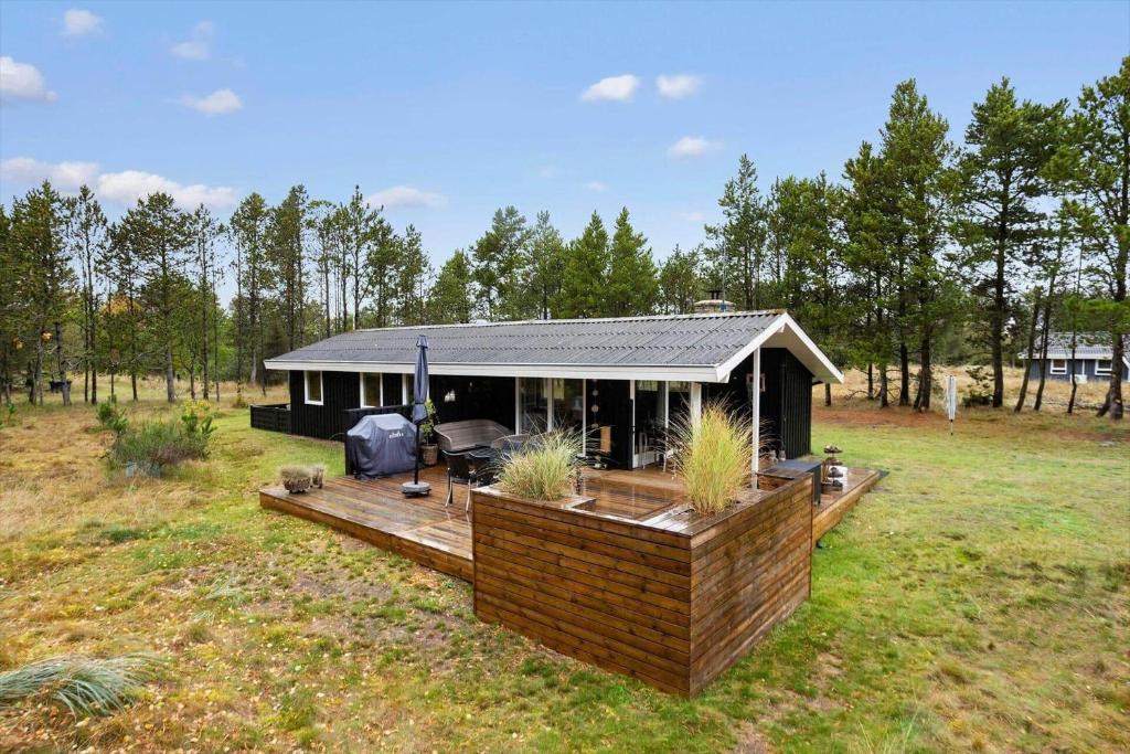 ein kleines Haus mit einer Terrasse auf einem Feld in der Unterkunft TV1689 Strandby - Klitmarken 4 in Strandby