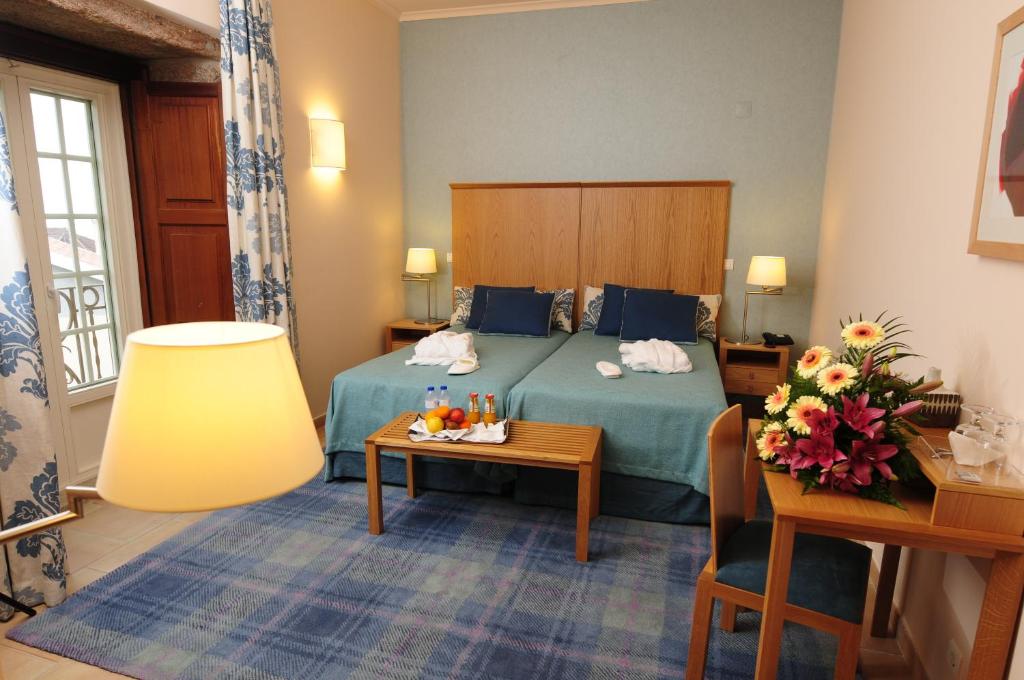 um quarto de hotel com uma cama e uma mesa em INATEL Linhares da Beira Hotel Rural em Linhares