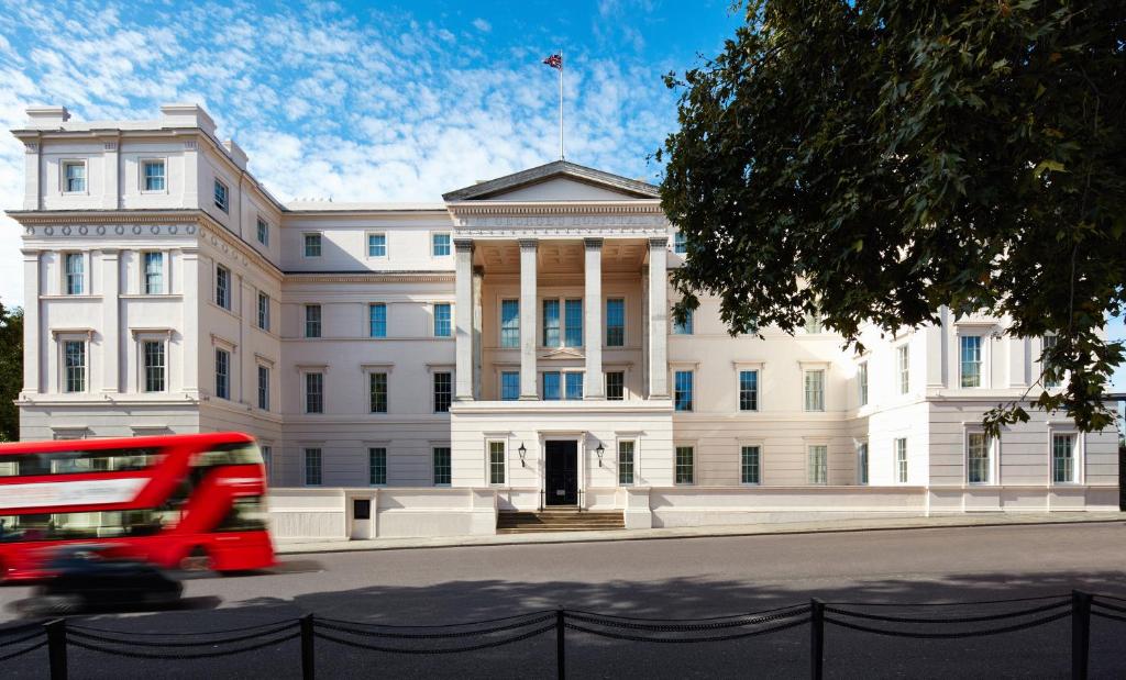 a red double decker bus in front of a building at The Lanesborough, Oetker Collection in London