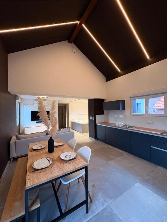 Una cocina y una sala de estar con mesa y sillas. en Gite Spa L'Atelier Emile - Spa Privatif - 5 min COLMAR, en Sainte-Croix-en-Plaine