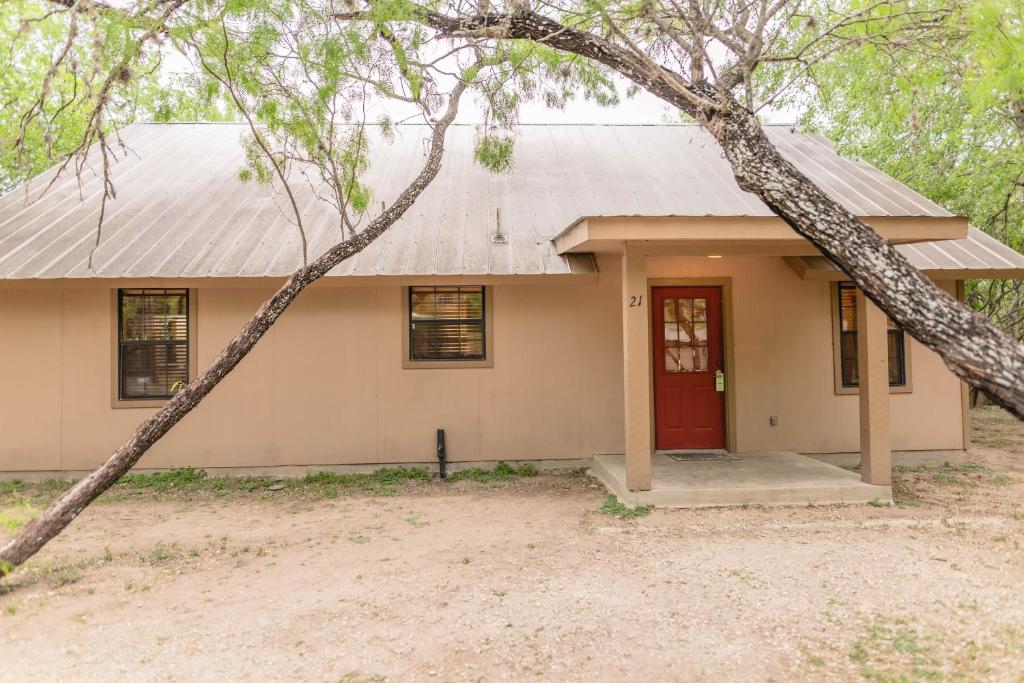 una piccola casa con una porta rossa e alberi di Frio Country #21 a Concan