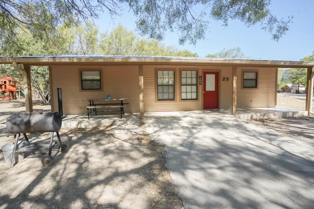 una piccola casa con una porta rossa e un tavolo di Frio Country #23 a Concan