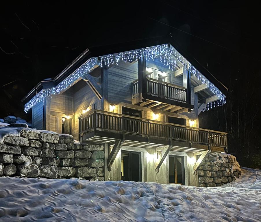 a house with a deck in the snow at night at Chalet du Bonheur in Bonnevaux
