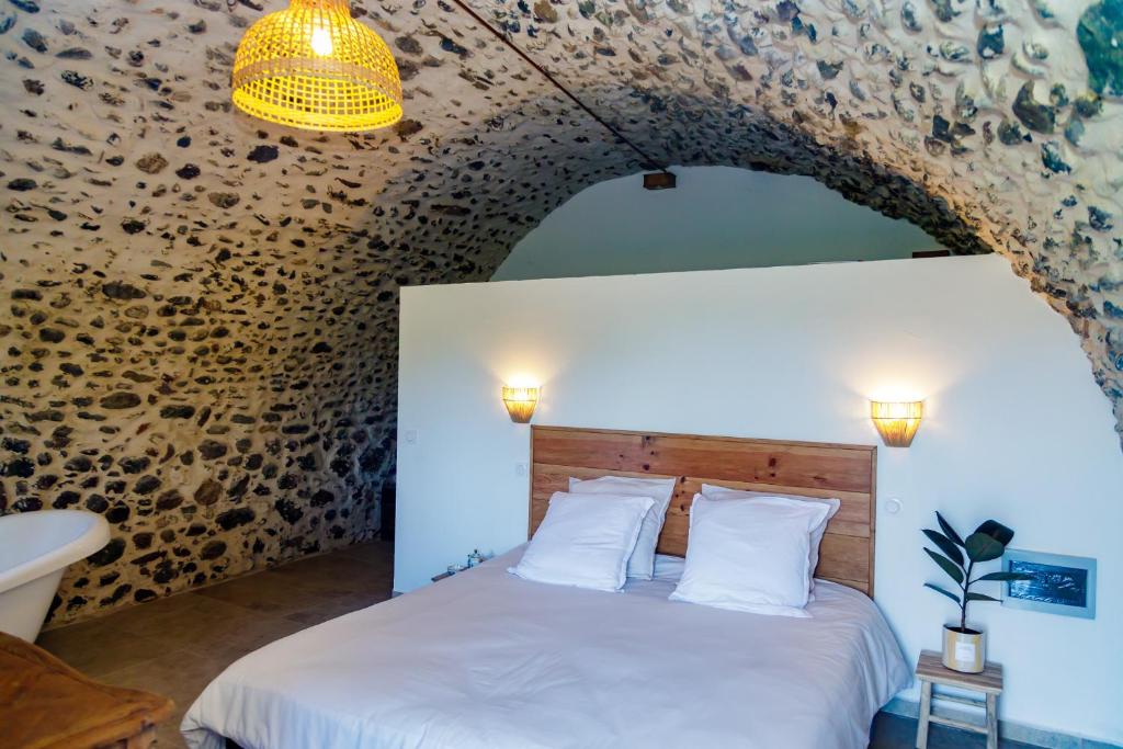 - une chambre avec un lit blanc et un mur en pierre dans l'établissement Suite du Domaine Marquiliani, à Fautea