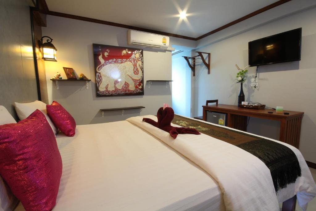1 dormitorio con 1 cama blanca grande con almohadas rojas en TR Guesthouse, en Sukhothai