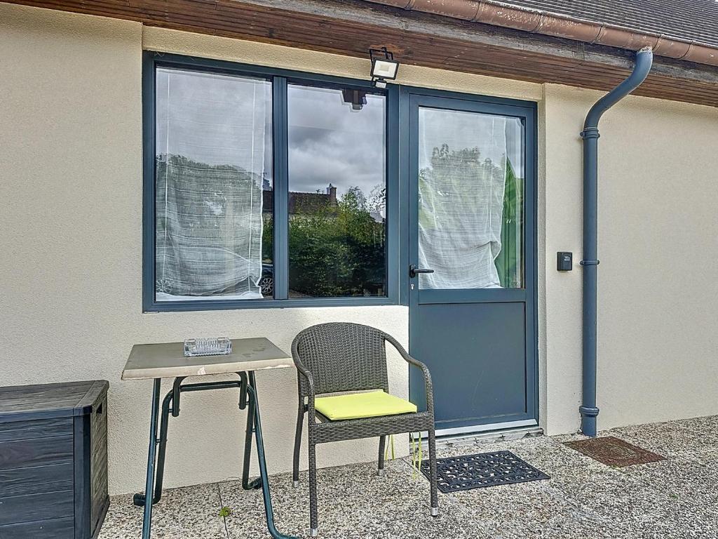 a chair and a table in front of a window at Maisonnette 36m2 à 5 minutes de Chantilly in Vineuil-Saint-Firmin