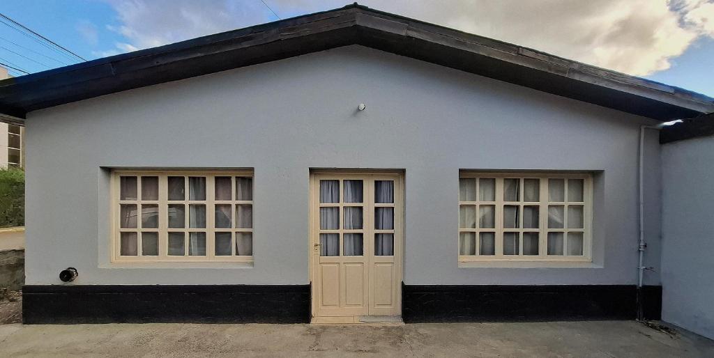 a white house with two windows and a door at La Casita del Molino in Trevelin