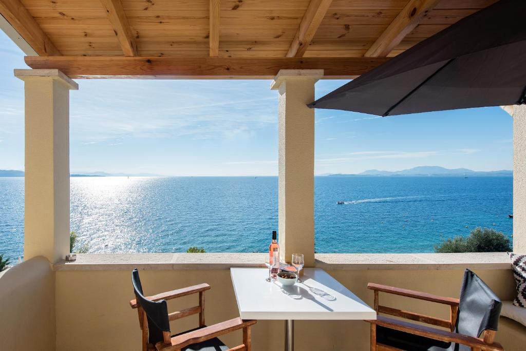 a table and chairs on a balcony with a view of the ocean at Krouzeri Beach Apartments in Nisakion