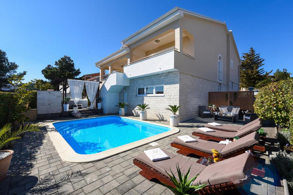 a villa with a swimming pool in front of a house at My Dalmatia - Sea view Villa Bella with private heated pool and jacuzzi in Kokić