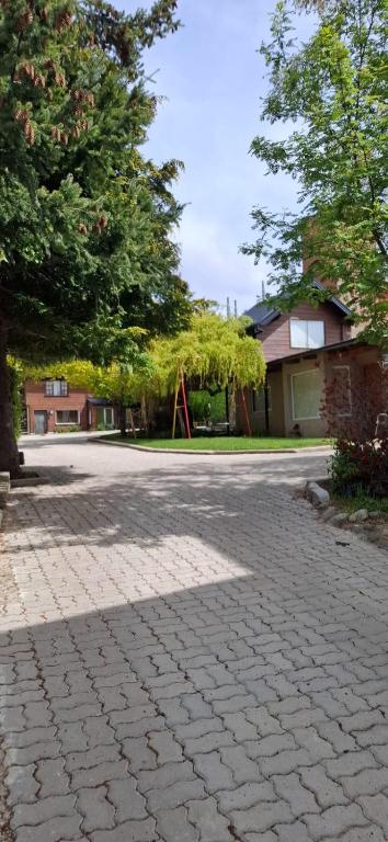 a brick street with a tree and a playground at La Fontana Cabañas in San Carlos de Bariloche