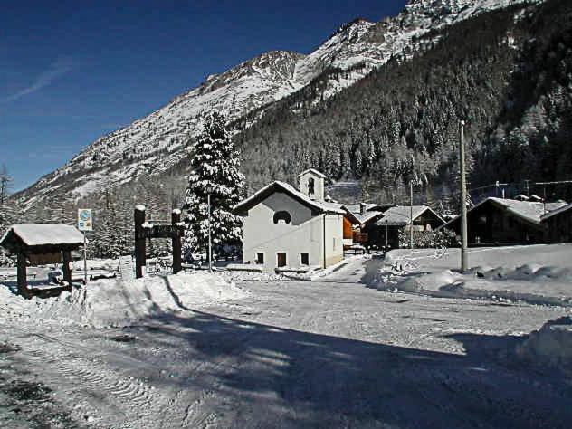 a snow covered building with a mountain in the background at Case Gran Paradiso Rhemes Notre Dame Carré in Rhêmes-Notre-Dame