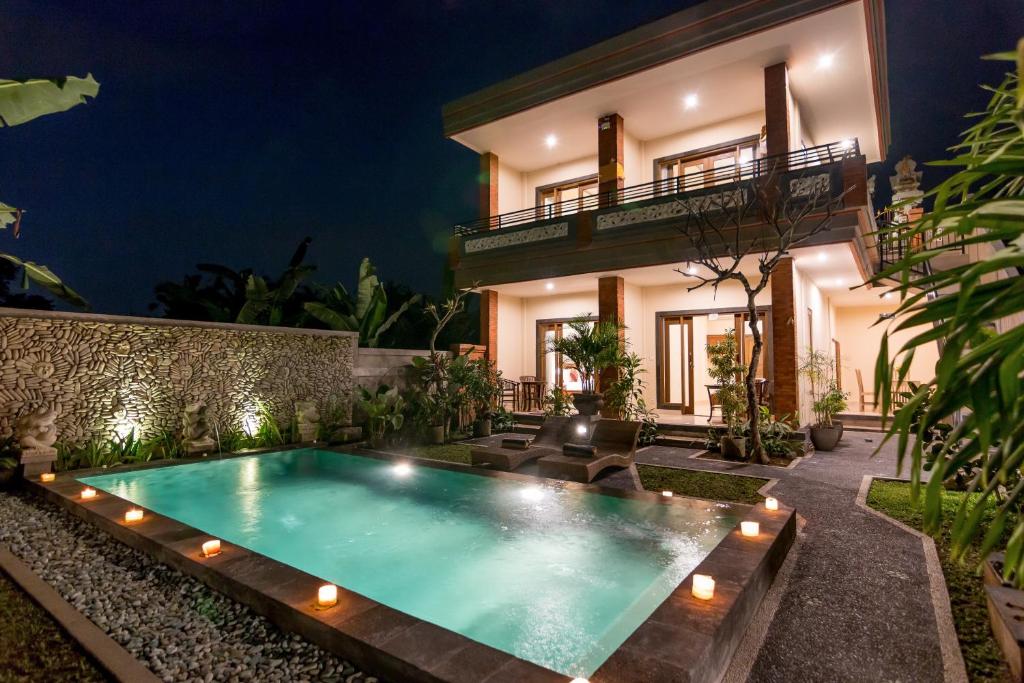 a villa with a swimming pool at night at Umah Dangin Guest House in Ubud
