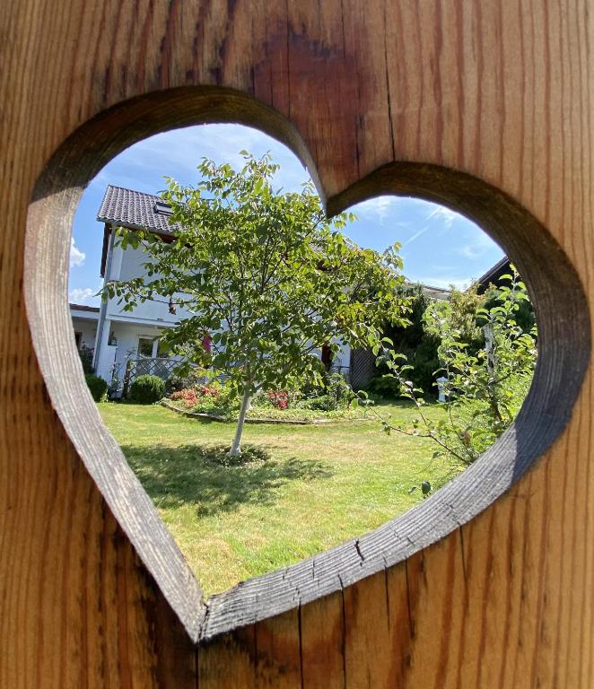 a heart shaped window on a wooden wall with a tree at FeWo im Dreiländereck in Büchlberg