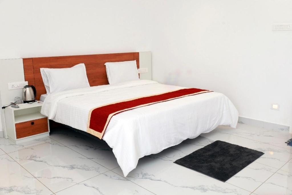 a bedroom with a large bed with a red and white blanket at Dreams Holidays Vagamon in Vagamon