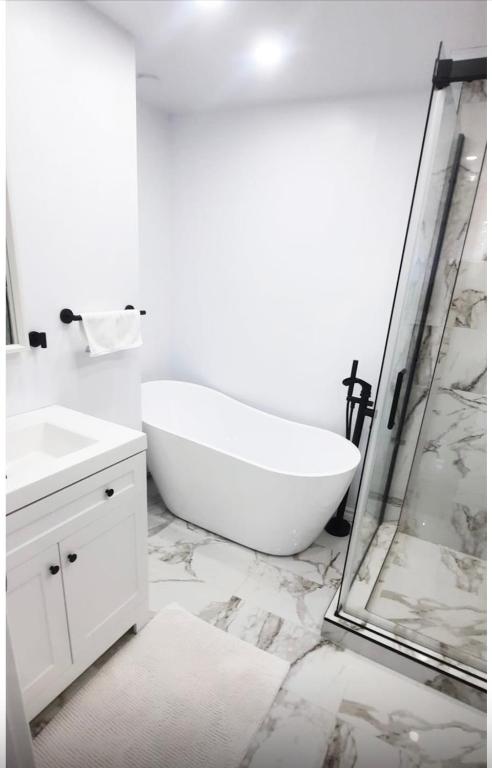 a white bathroom with a tub and a shower at Cute 2 BDR condo in Montreal