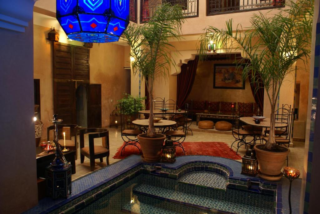 una stanza con piscina, tavoli e lampadario a braccio di Riad Lapis-lazuli a Marrakech