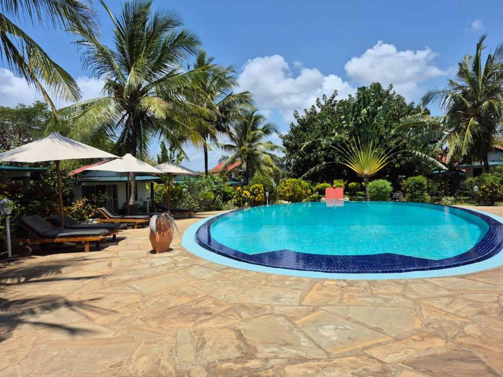 a swimming pool in a resort with palm trees at African Dream Cottages - Diani Beach in Diani Beach
