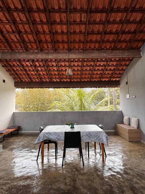 a table with chairs in a room with a large window at Chalé com Varanda Grande e Terraço Vista Mar in Itanhaém
