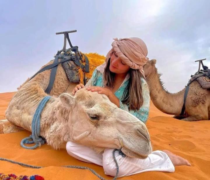 a girl is sitting on a camel in the desert at Sunlight Luxury Desert Camp in Merzouga