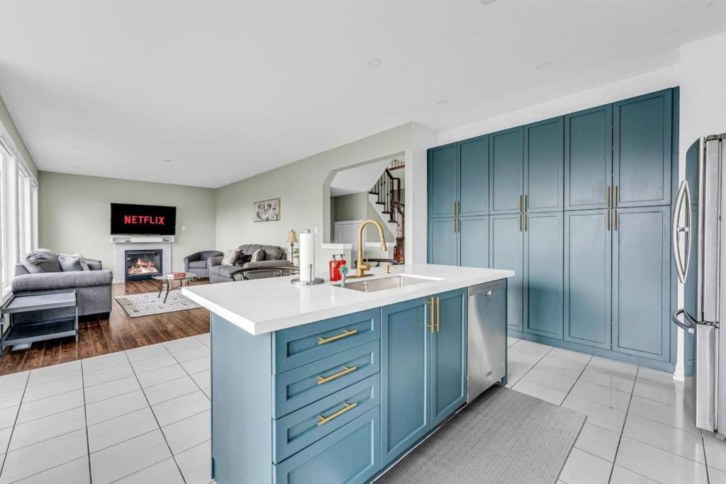 a kitchen with blue cabinets and a living room at Luxury Mansion with Chefs Kitchen by Niagara Falls in Thorold